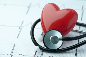 Red heart with a stethoscope on a printed EKG